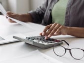 Woman accountant using calculator and computer.