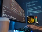 Hands typing on keyboard in front of computer monitor.