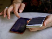 Woman navigating two iphones at the same time.