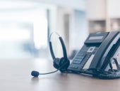 A phone and headset on a desk.